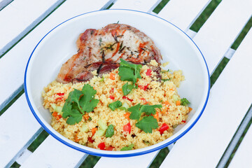 close up of Couscous mediteranean food with vegetable served with piece of grilled pork, isolated on white background.