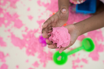 Children's hands playing pink science sand