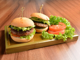 two baked mini chicken / pork / beef meat burger bun and vegetables salad on wood table fresh halal pastry sandwich menu