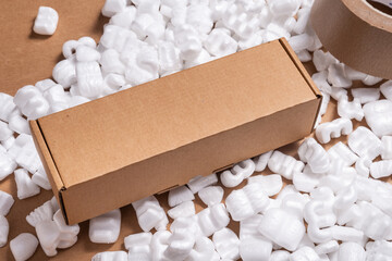 Cardboard box on loose white Filler Shipping Packing Peanuts - obrazy, fototapety, plakaty