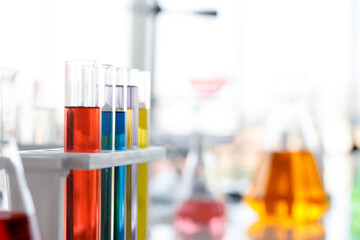 Anonymous scientist in pipette pouring green liquid into glass test tube while conducting chemical research in laboratory