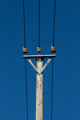 Obraz premium Wooden electric pole with electric wires with blue sky in the background. Electricity concept