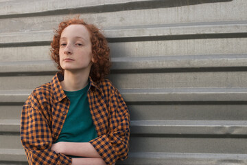 An empty space for the text. A teenager of 12-14 is standing by a gray metal wall.
