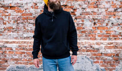 City portrait of handsome guy wearing black blank hoodie and baseball cap with space for your logo...