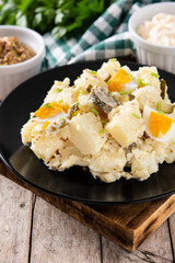Potato salad with gherkins, egg and mustard on wooden table