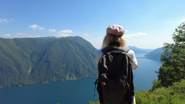 Photographer woman taking pictures with camera on top of Lugano city by Lugano Lake in Switzerland. Aerial view lookout from Monte Bre Mount. Lugano cityscape with San Salvatore mount in Ticino canton