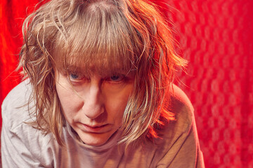 Portrait of serious sad middle-aged woman on red background. Unprofessional female model in the...