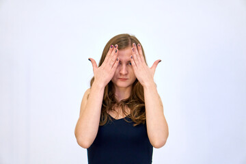 Fototapeta na wymiar Hold on to your head. Be shocked and surprised. A beautiful Caucasian woman stands on a white background in a blue sweater with loose hair. The woman shows emotions.