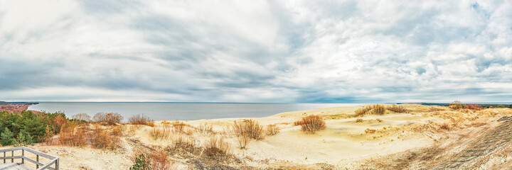 Fototapeta na wymiar Sand dunes of the Curonian Spit in the cloudy weather with the sky covered with clouds on the shore of the Curonian Bay