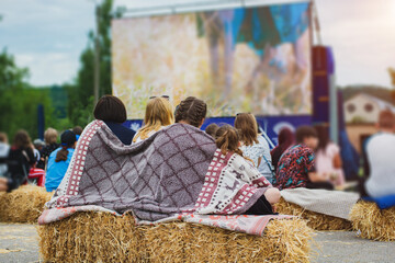 Three girls watching a movie in the open air, wrapped in a blanket