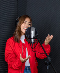 Ethnic female singer in headphones singing in microphone and recording music in studio