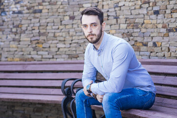 Portrait of a man who sits on a bench and thinks