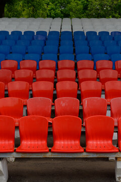 the stands of a small stadium with rows of white, blue and red seats