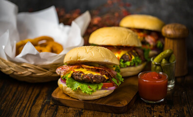 Selective focus on hamburgers with beef burgers, fried onions, spinach, ketchup, pepper and cheese served side dishes on a wooden board with soft drink.