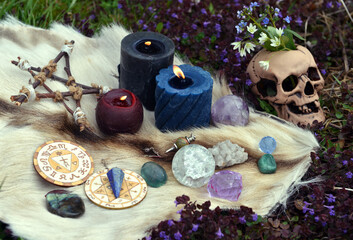 Beltane still life with ritual objects, skull, burning candles, pentagram and crystals outside.