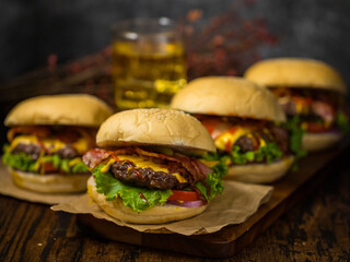 Beef hamburgers served on a wooden board with beer in loft background