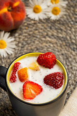 Close-up of yogurt with strawberry, peach and chia in a black ceramic cup. Healthy and tasty breakfast.