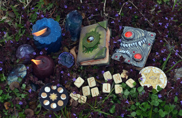 Still life with witch magic books, runes, crystals and burning candles outside.