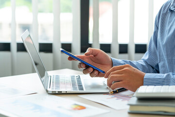 Close up account man hand using a smartphone to check your company's income, expenses, and taxes, ..financial reporting and business performance to check investment results