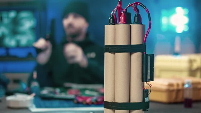Dangerous man out of focus camera checks weapon. In the foreground a bomb.