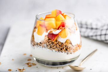 Greek yogurt parfait with granola and peach in a glass. Healthy vegetarian food - 442489927