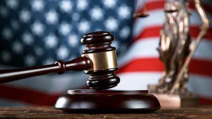 Gavel being struck to decide an auction or guilty verdict in court. USA flag on background. Close-up.