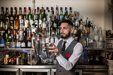 Professional barman with shaker preparing alcoholic drink