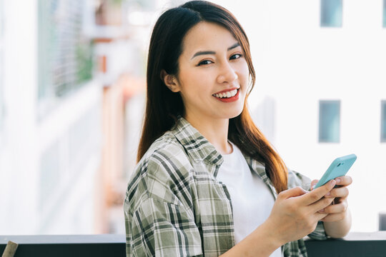 Portrait of young Asian woman using smartphone at home