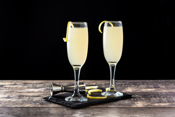 French 75 cocktail in glass on wooden table and black background