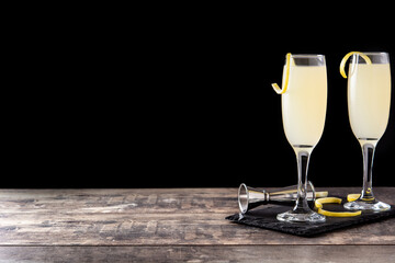French 75 cocktail in glass on wooden table and black background. Copy space