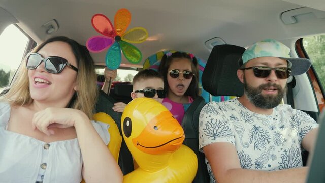 Happy active family having fun dancing sing songs while traveling by car on summer vacation