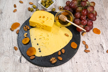 Cheese on a graphite board with dried apricots, nuts and olives. top view