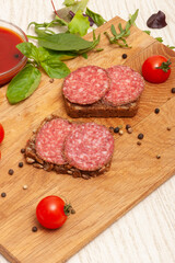 Smoked sausage, ketchup and greens on a wooden board. Top view