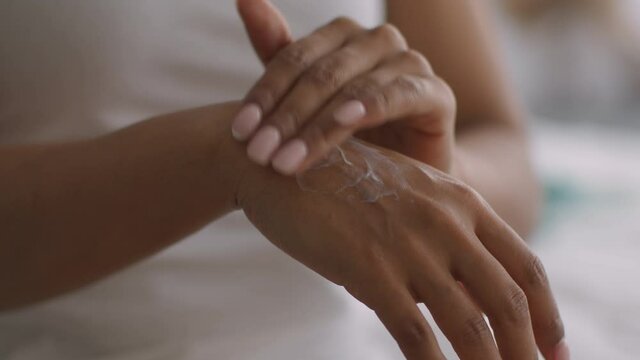 Young african american lady applying pampering foam lotion on hands, sunscreen protection concept, close up shot