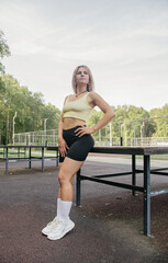 A blonde girl in a sports uniform stands next to a pingpong table