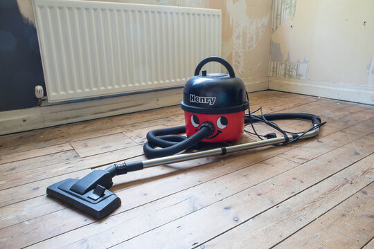 Peterlee, Great Britain - June 29th, 2021 : Red Henry suction vacuum cleaner in an empty room with wooden floorboards.