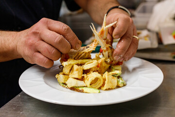 Chef mentre sistema la frittura di pesce appena cotta in un piatto bianco