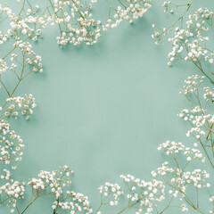 Flowers composition. White flowers on turquoise blue background. Wedding mockup with small flowers. Flat lay, top view, frame. Gypsophila Baby's-breath flowers