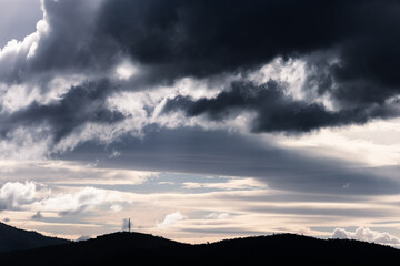 thick stormy clouds over the mountains with intense sunlight peaking through and contrasty tones