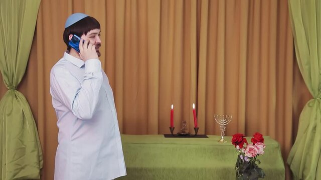 Before the chuppah ceremony, the Jewish groom speaks on the phone in the synagogue hall