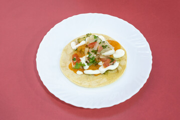 Fototapeta na wymiar Taco with a lot of coriander, various sauces, onion and pico de gallo on a white plate