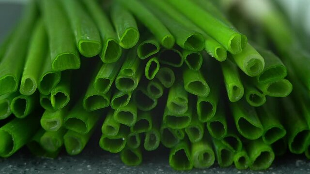 Camera movement on fresh cut green onions with water drops on black tray. Healthy and organic vegetables concept. Close up of greens. Macro food background