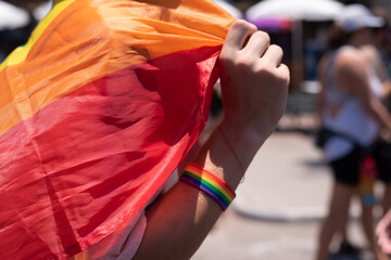 Obraz premium Man drees on hand bracelet of colors of rainbow. Close-up. Symbol of gays is colors of rainbow. Gay and pride solidarity parade in Tel Aviv.