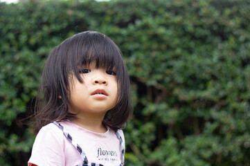 A headshot portrait of a cheerful baby Asian woman, a cute toddler little girl with adorable bangs hair, a child  smiling and pose for hand don't looking to the camera.