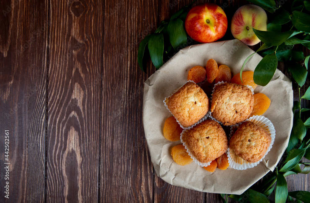 Aufkleber top view of delicious muffins and dried apricots on a plate and fresh sweet nectarines on wooden rus