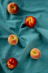 top view of fresh ripe nectarines and peaches scattered on blue fabric