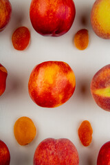 top view of fresh ripe nectarines and peaches with dried apricots on white background