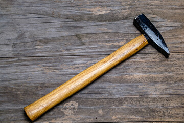 Hammer with a wooden handle on an old board. Close-up. Selective focus. Space for lettering and...