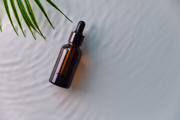 Glass serum cosmetic brown bottle with pipette in water