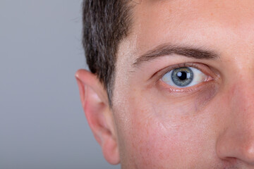 Close up of blue eye of caucasian businessman, isolated on grey background